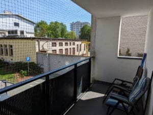 Estetyczna, beżowa siatka balkonowa z oczkiem 40x40 mm, klejona na balkonie pierwszego piętra w Warszawie. Bez wiercenia i uszkadzania balustrady.