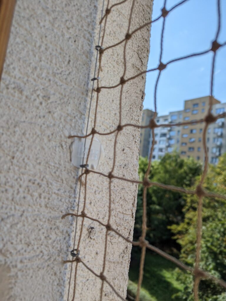 Metoda instalacji siatki na balkon. Na zdjęciu widać przyklejony zaczep z poliwęglanu do którego zamontowana jest linka stalowa, do której doszyta jest siatka.