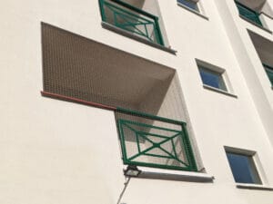 Siatka na balkonie widoczna z chodnika. Balkon typu loggia i siatka o oczku 4 cm niemal niewidoczna z zewnątrz, montaż w Warszawie.